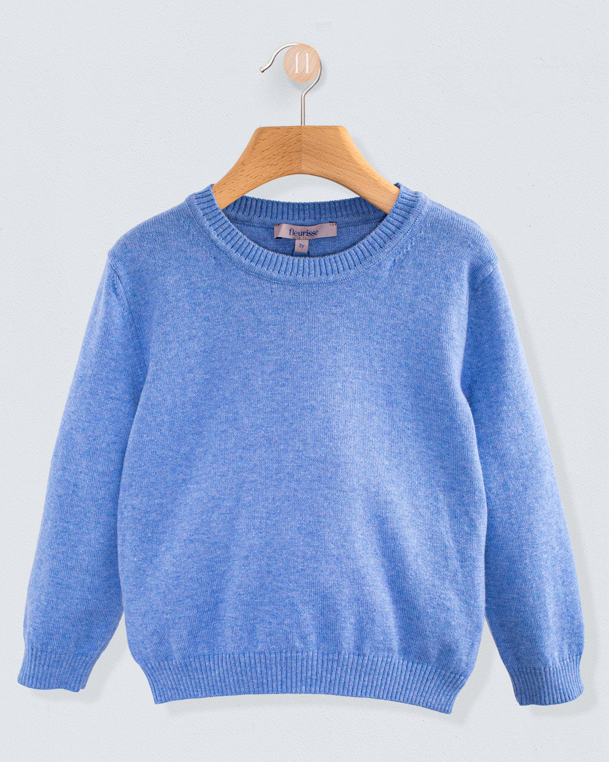Front view of the Arthur Mélange Cotton Crew Neck sweater in jean color with a ribbed crew neckline and cuffs hanging on a wooden hanger