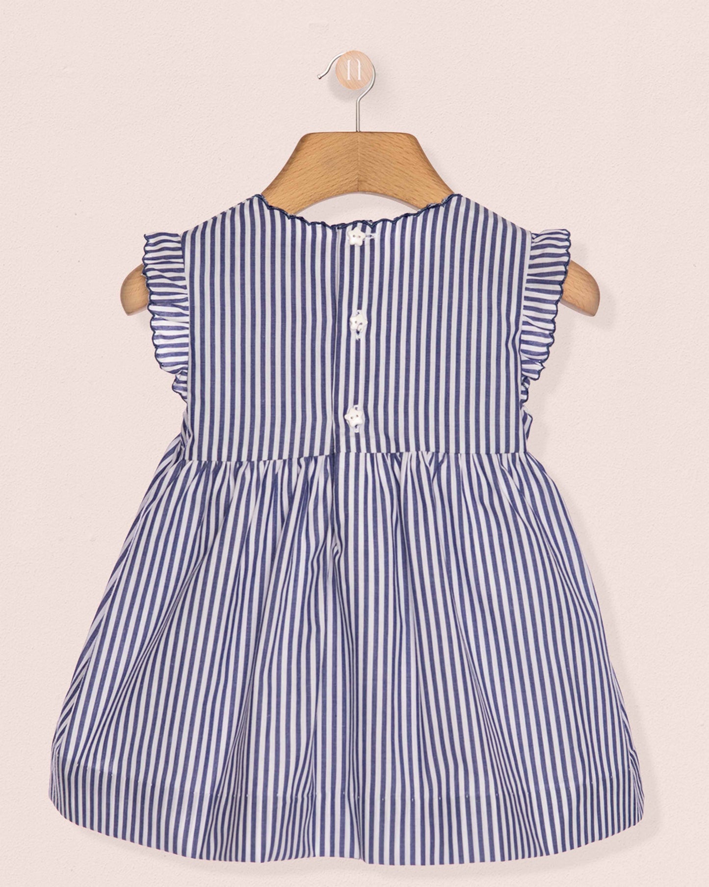 Blue and white striped dress on a hanger against a beige background
