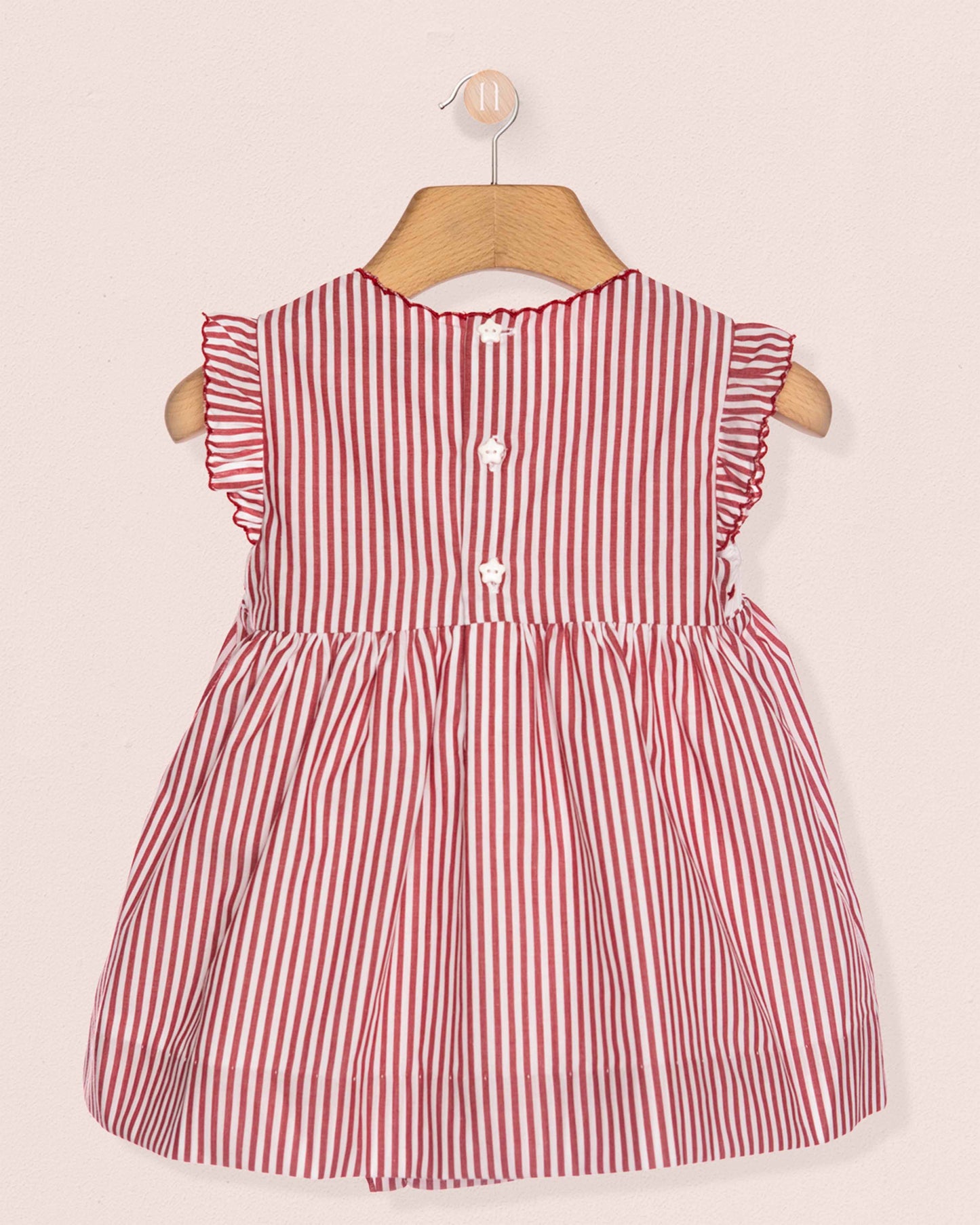 Red and white striped dress on a wooden hanger against a light pink background