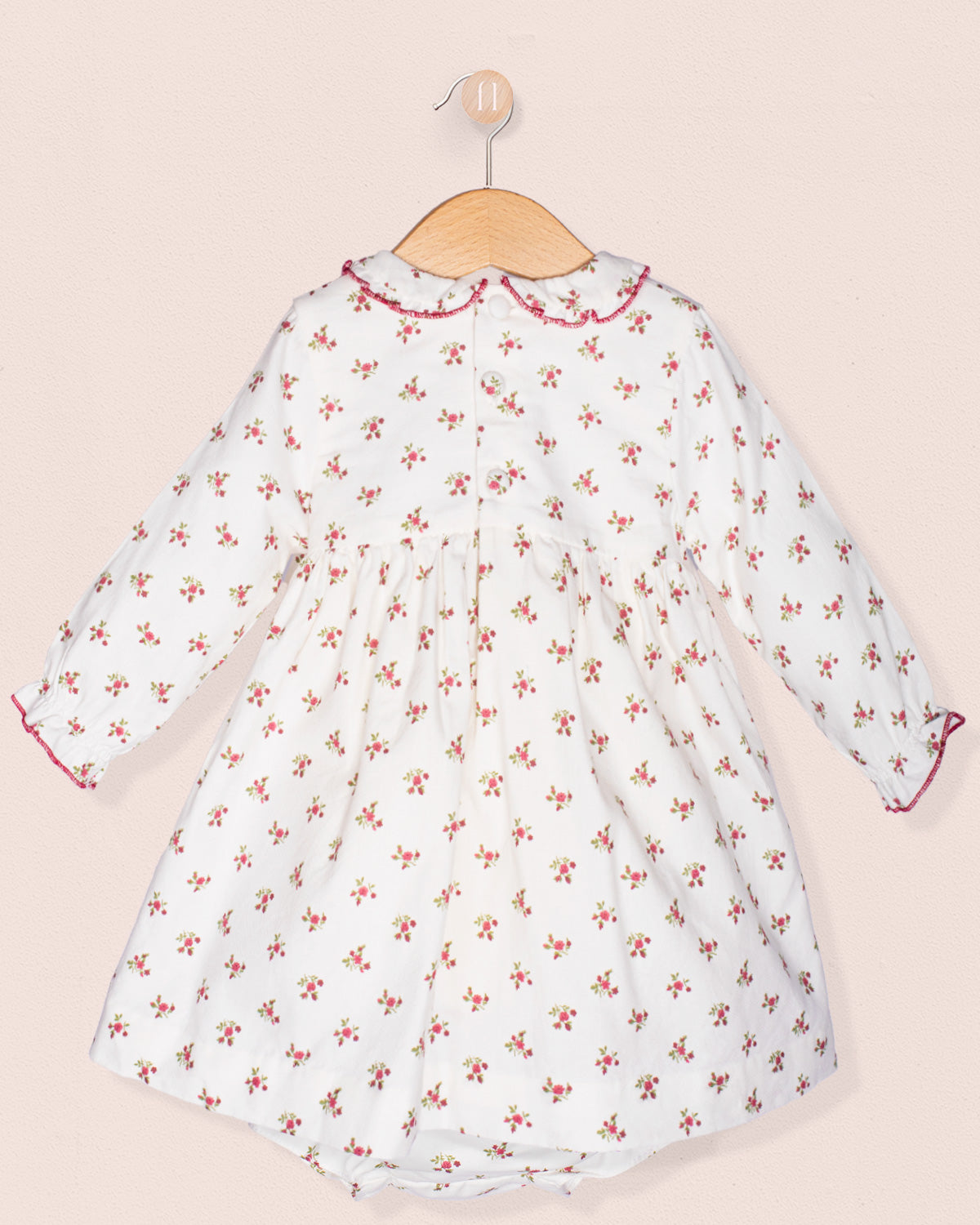 White dress with red floral pattern on a beige background