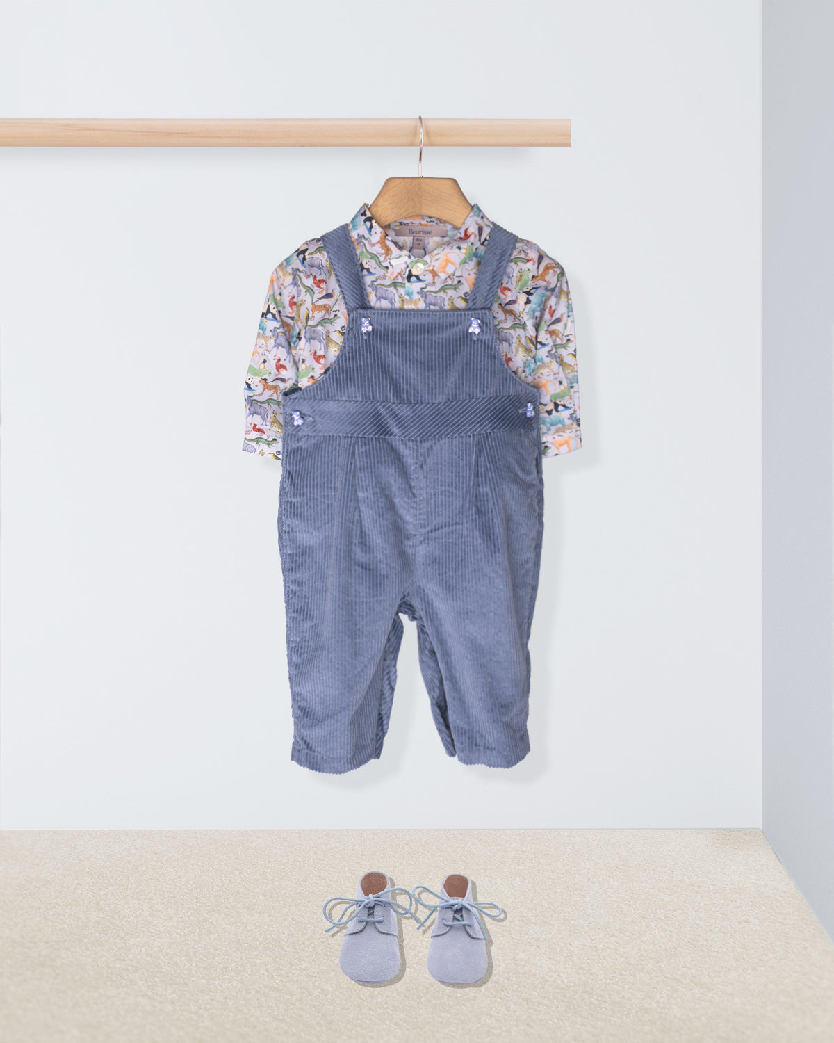 Children's outfit with blue checkered overalls, floral shirt, and shoes on a white background