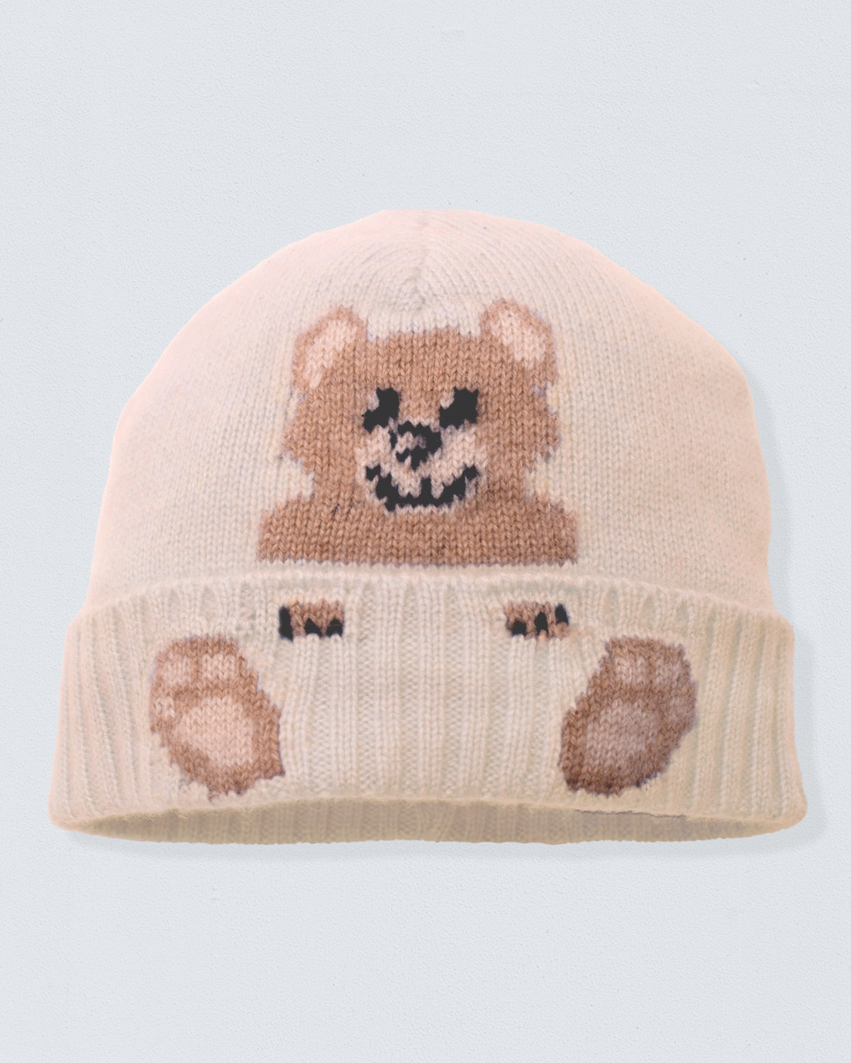 Knitted beige beanie with bear design on a light gray background