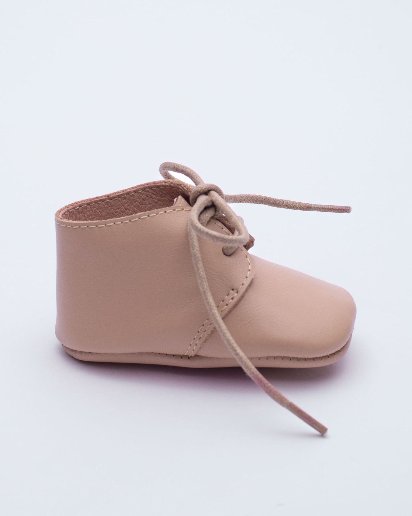Beige baby shoe with lace on a white background