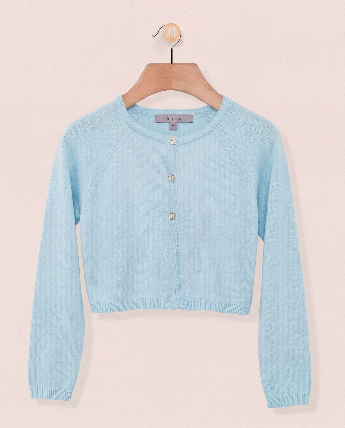 Light blue cardigan on a hanger against a light pink background