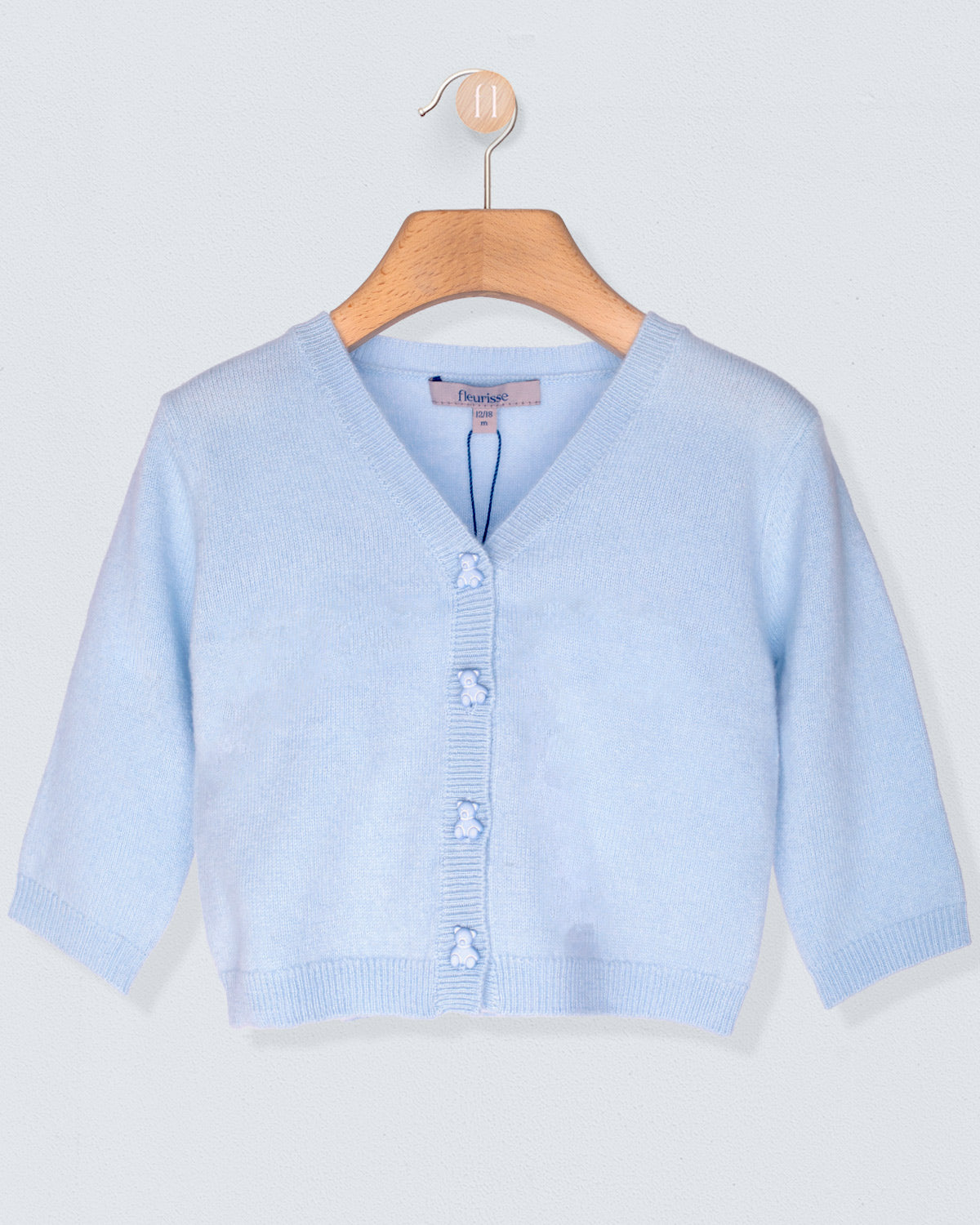 Light blue cardigan on a wooden hanger against a light gray background
