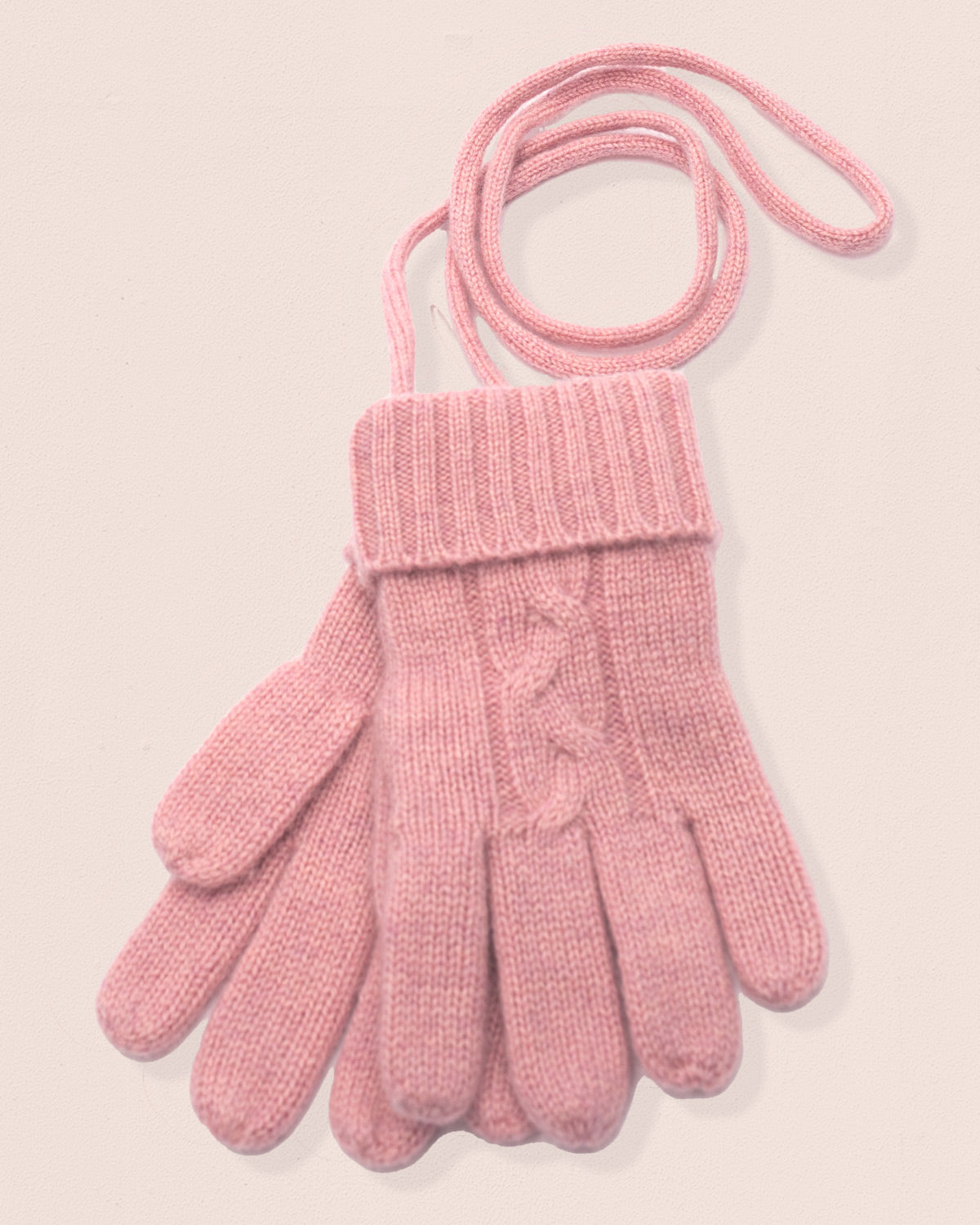 Pink-rose colored knitted gloves with a cable pattern on a light pink background