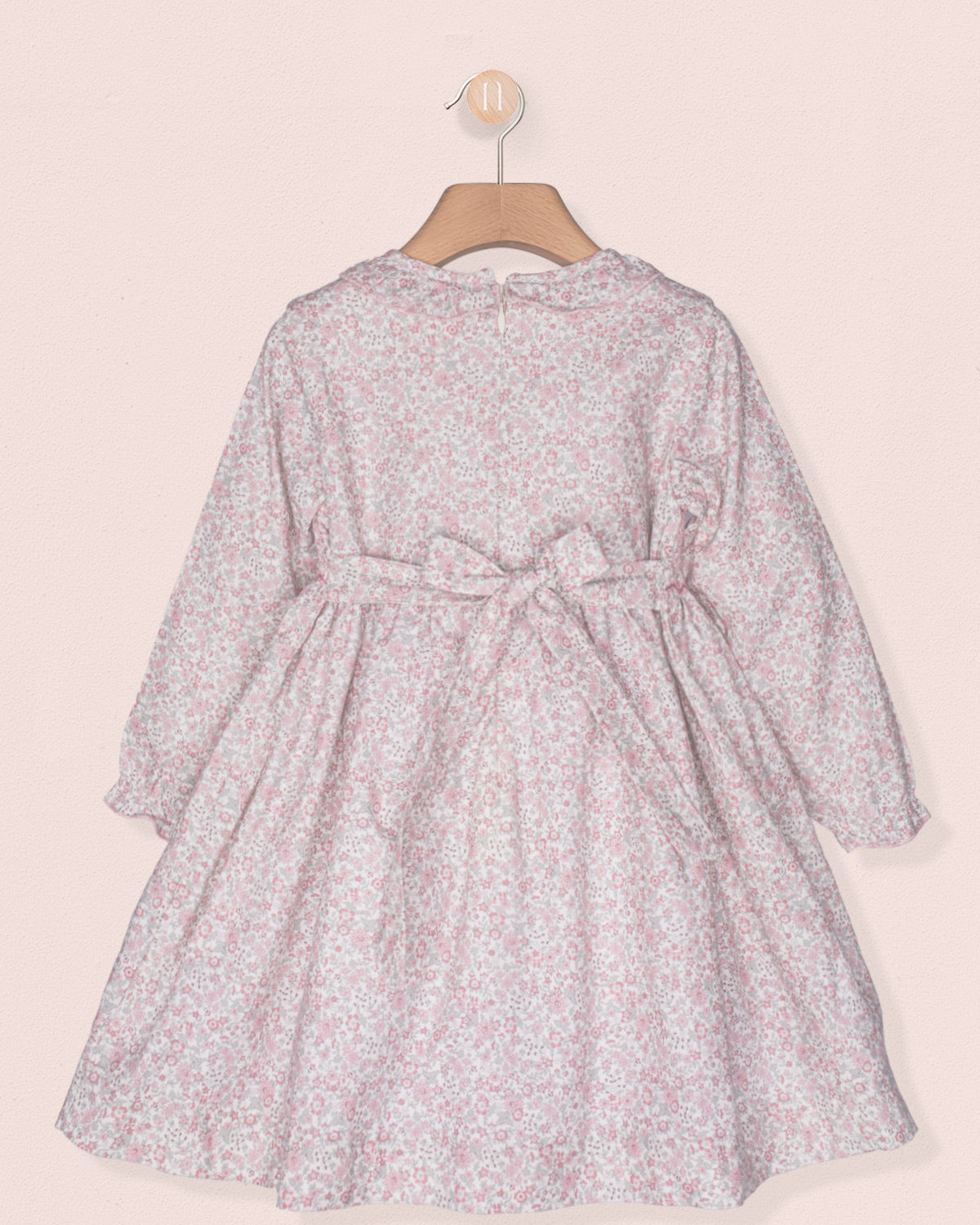 Floral dress on a hanger against a light pink background