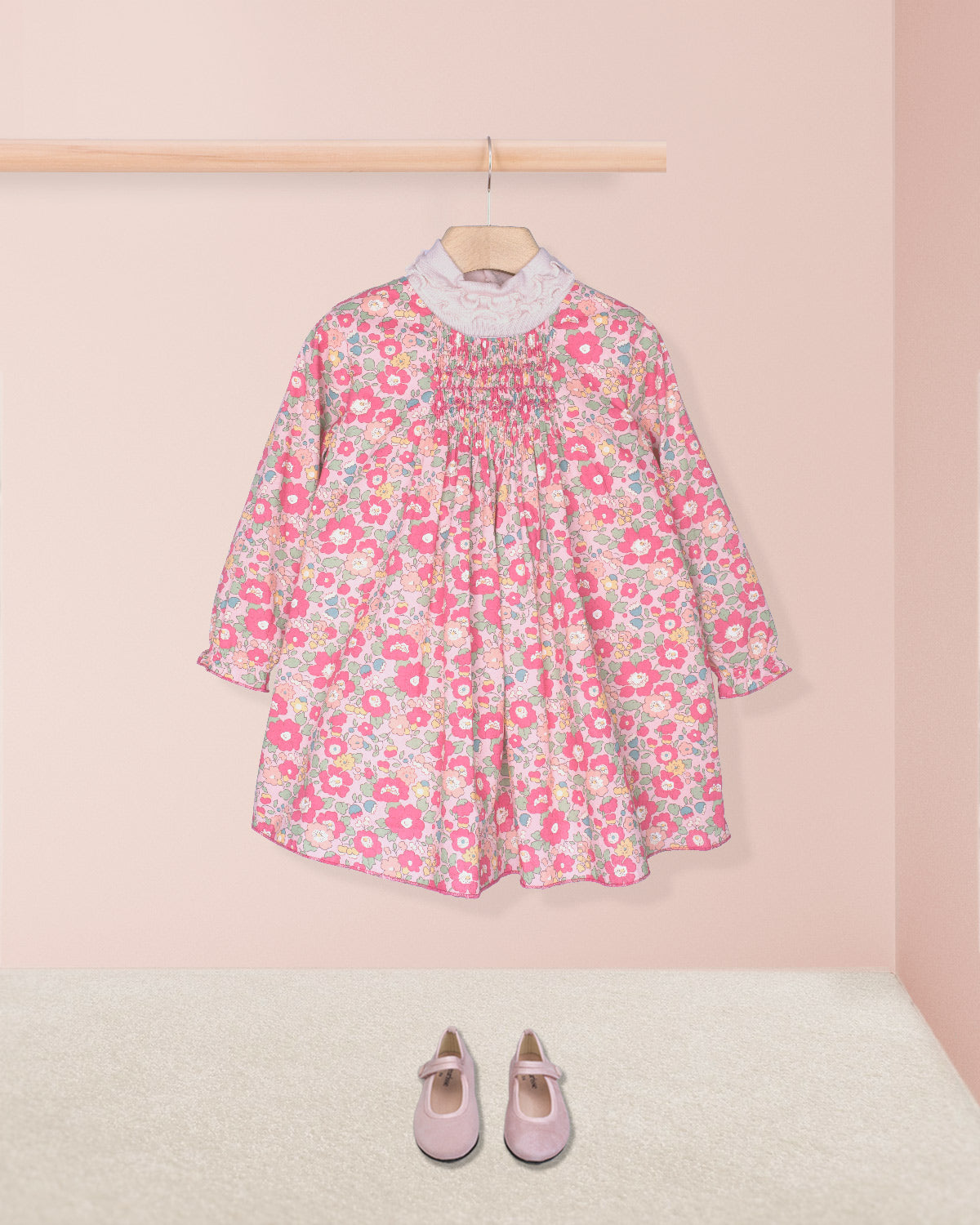 Floral dress on a hanger with pink shoes on a light pink background