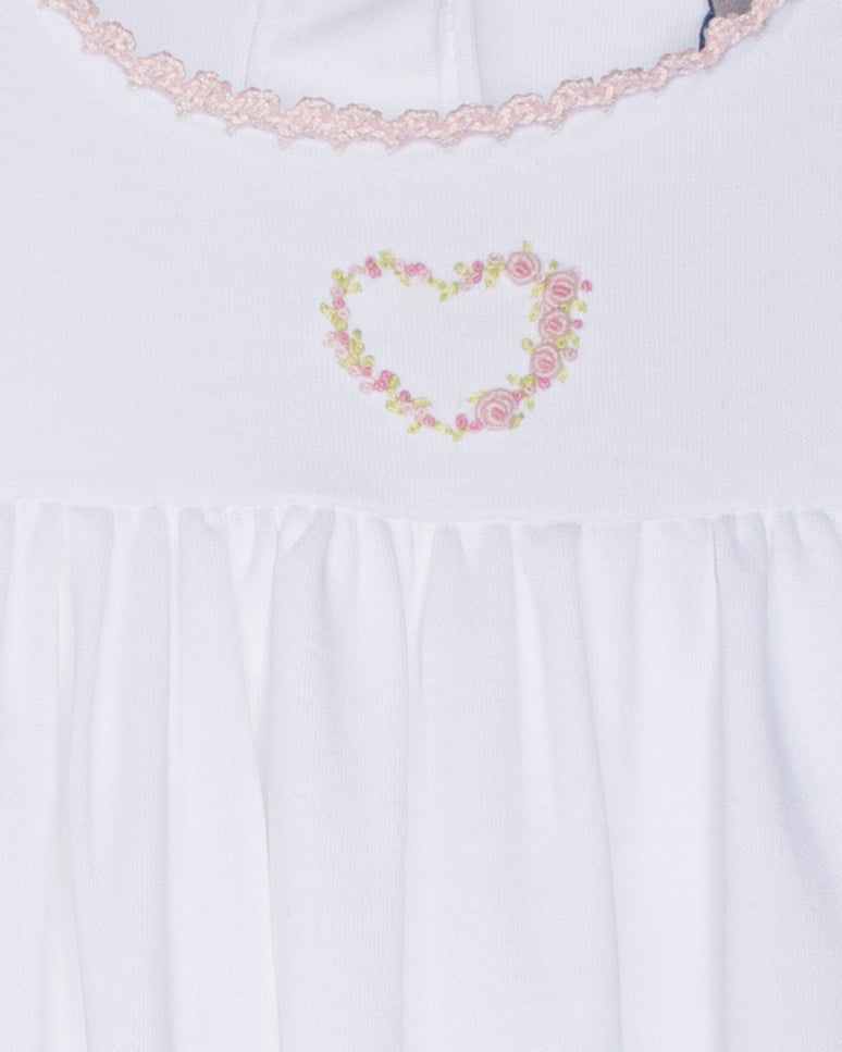 White gown with floral heart design and lace trim on a white background