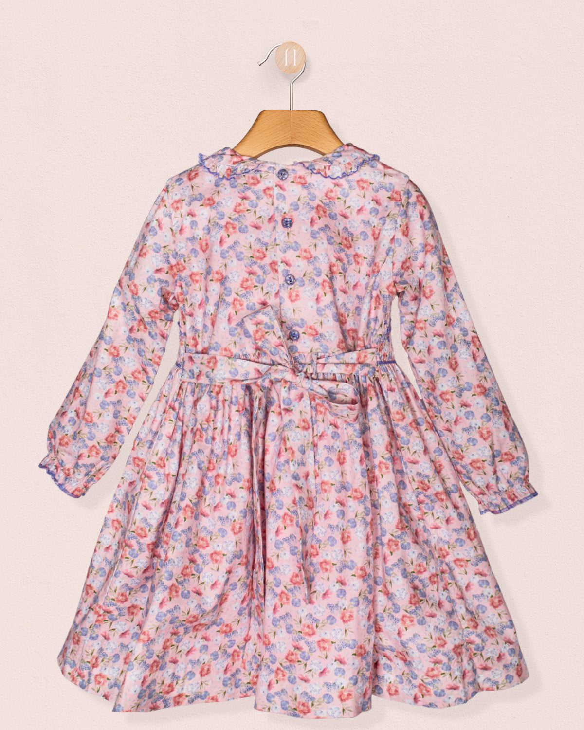 Floral dress on a hanger against a light pink background