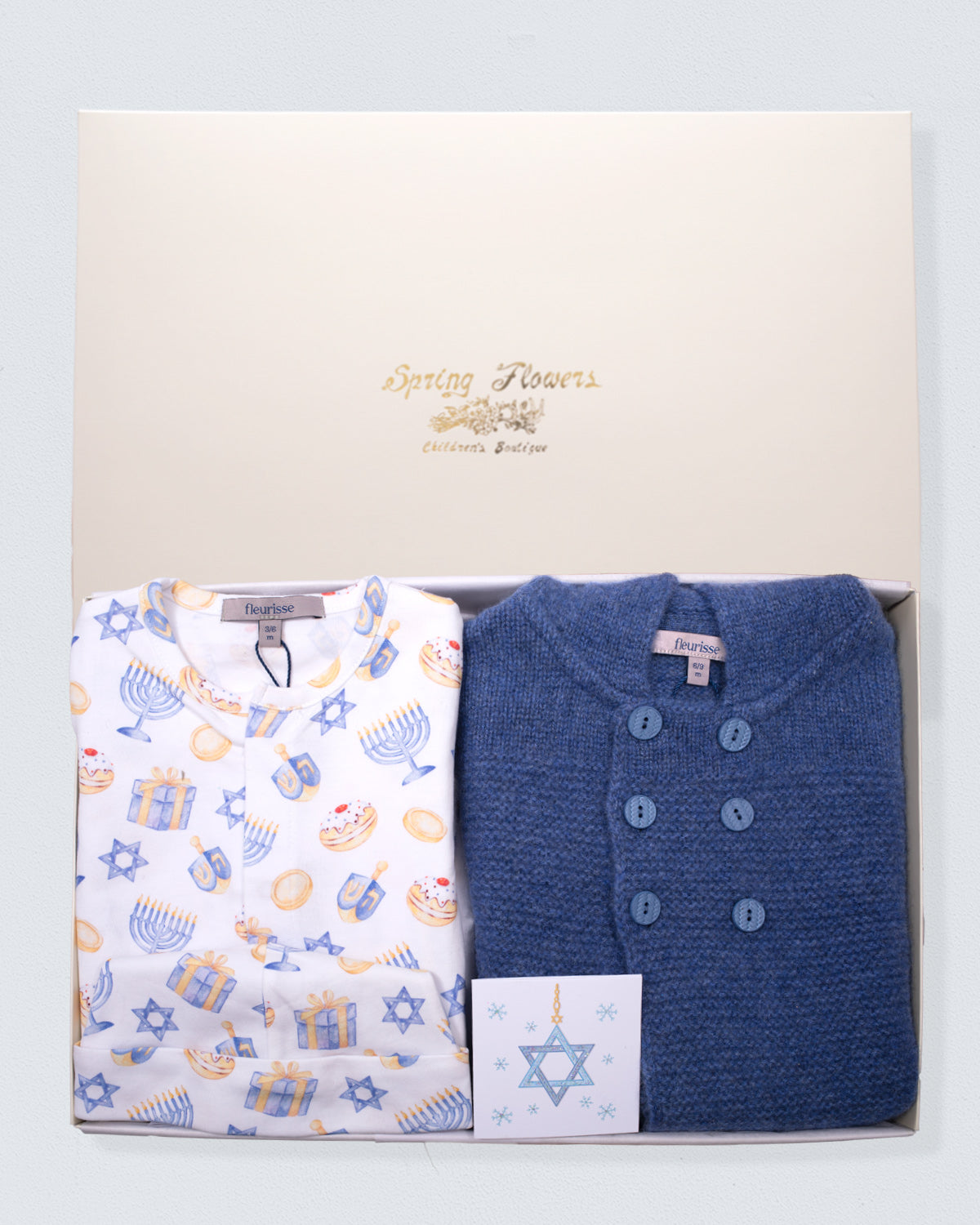 Two baby hanukkah print clothes in a box with 'Spring Flowers' branding on a light gray background