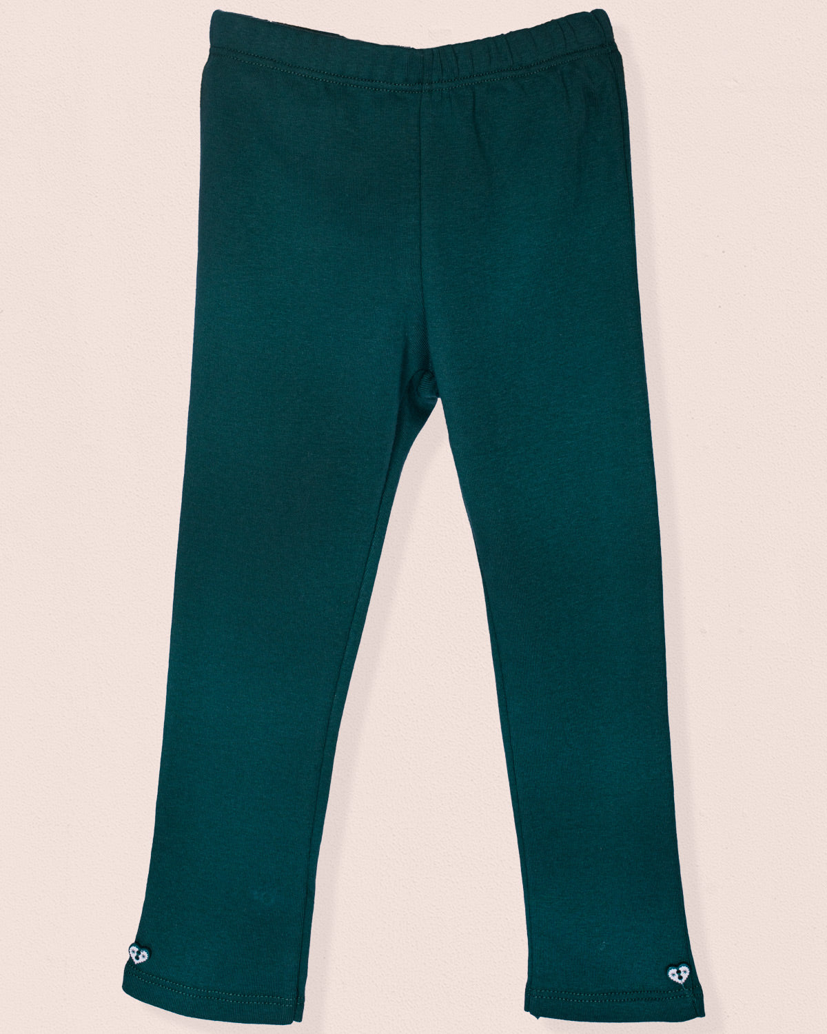 A pair of hunter green brushed cotton leggings displayed flat against a light beige background. The leggings feature a smooth elastic waistband and small heart-shaped button details at the ankle cuffs. Made from soft Italian jersey with a cozy brushed interior.