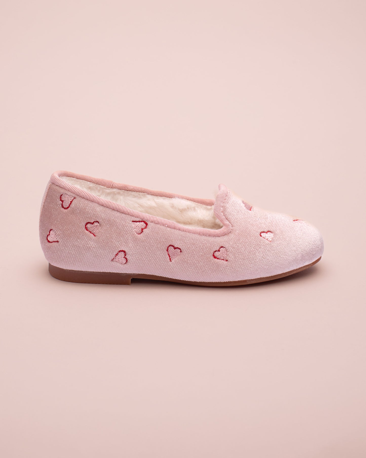 Pink shoe with heart patterns on a pink background