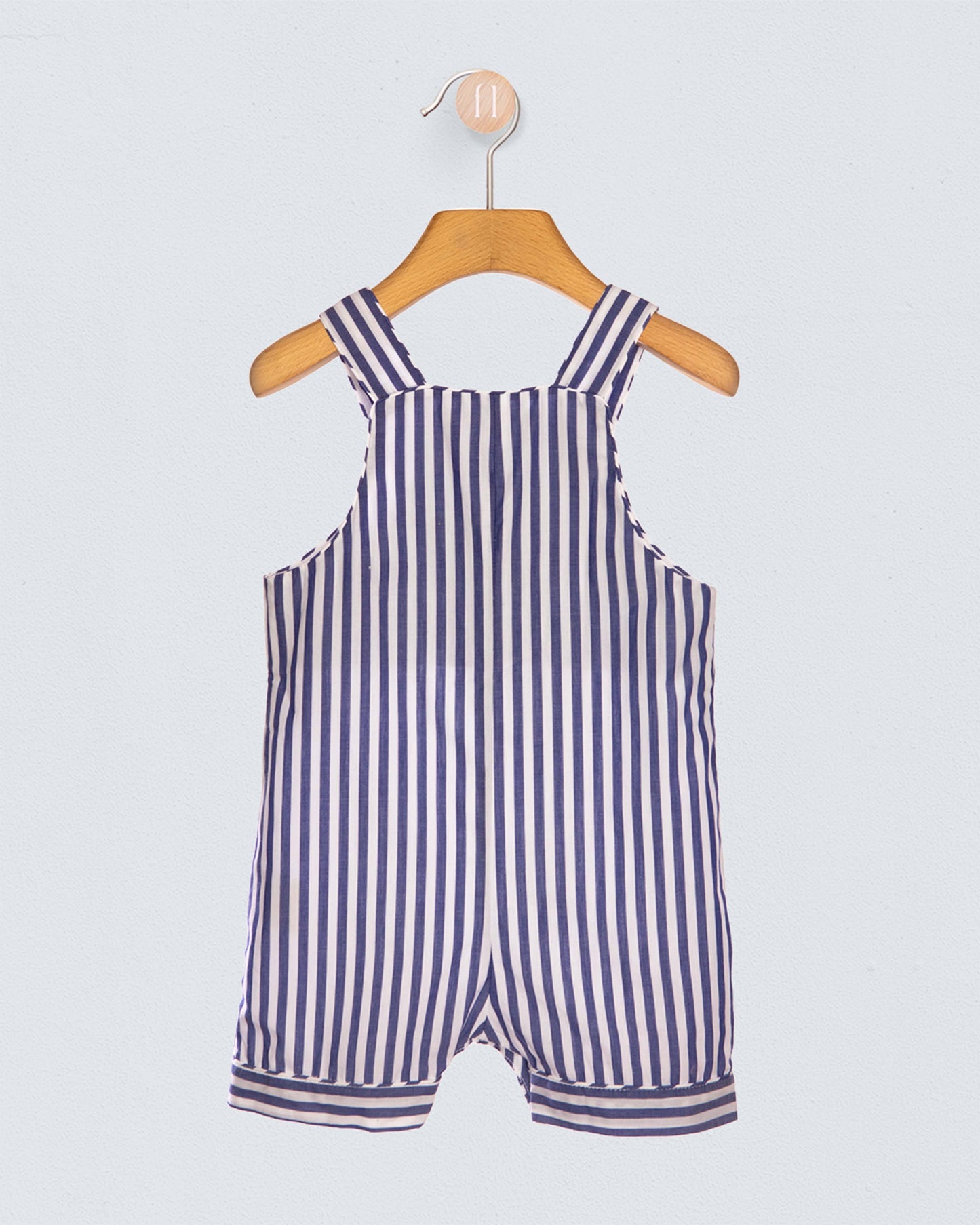 Navy and white striped romper on a wooden hanger against a light gray background