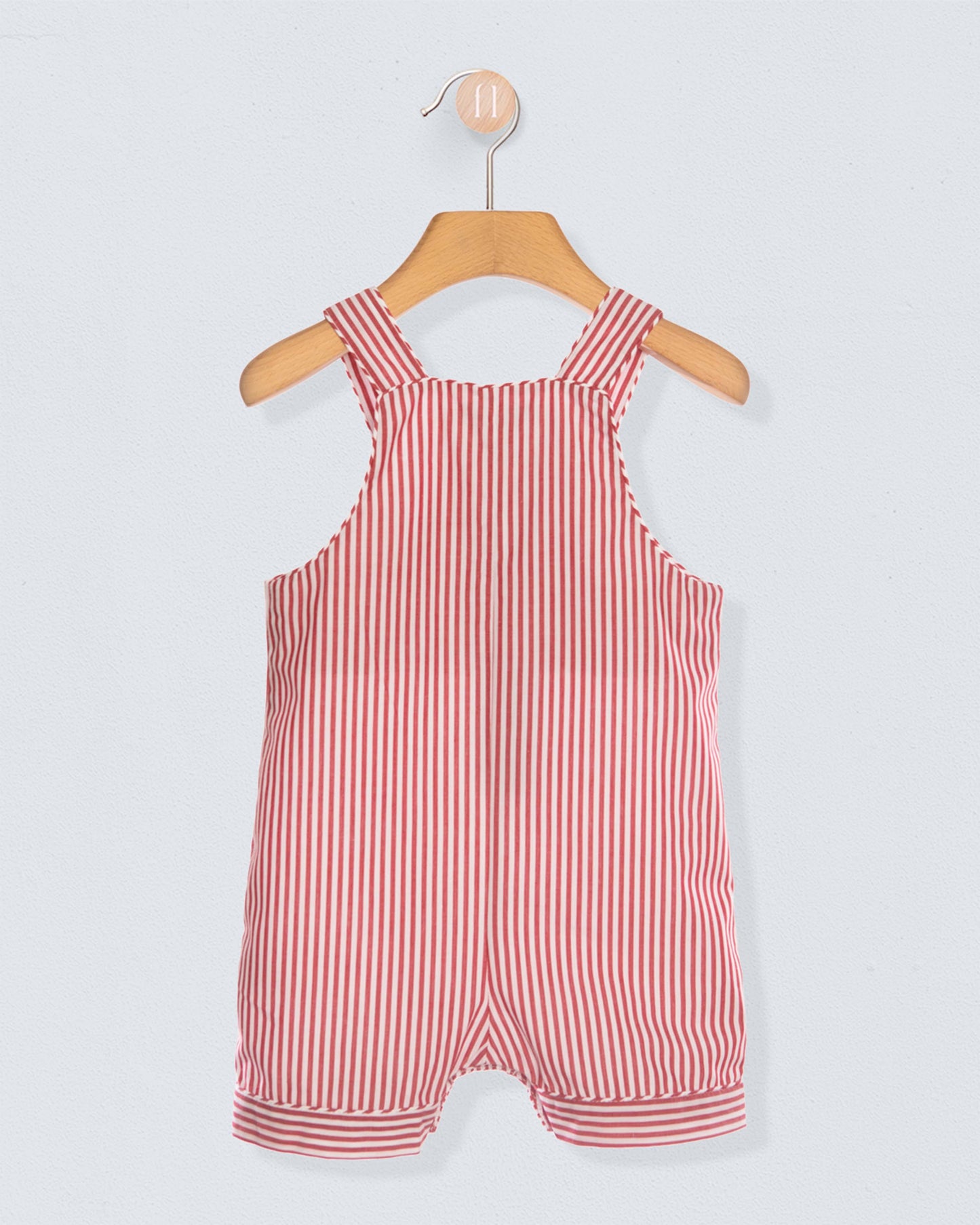 Back of red and white striped shortall on a wooden hanger against a light gray background