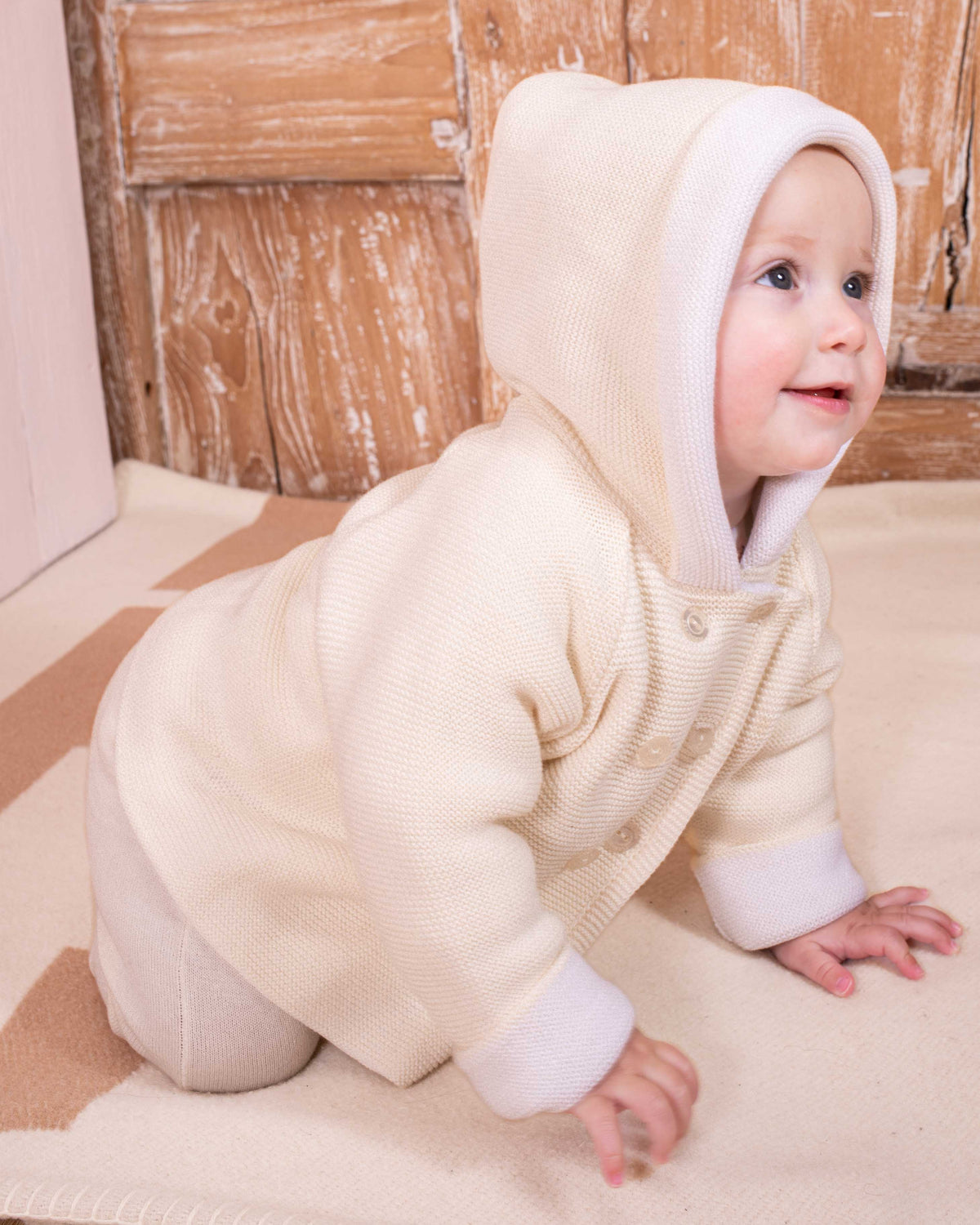 Baby wearing Jackpot Cream and White Hooded Sweater with matching Jackpot cream pant- crawling showing the side of the jacket