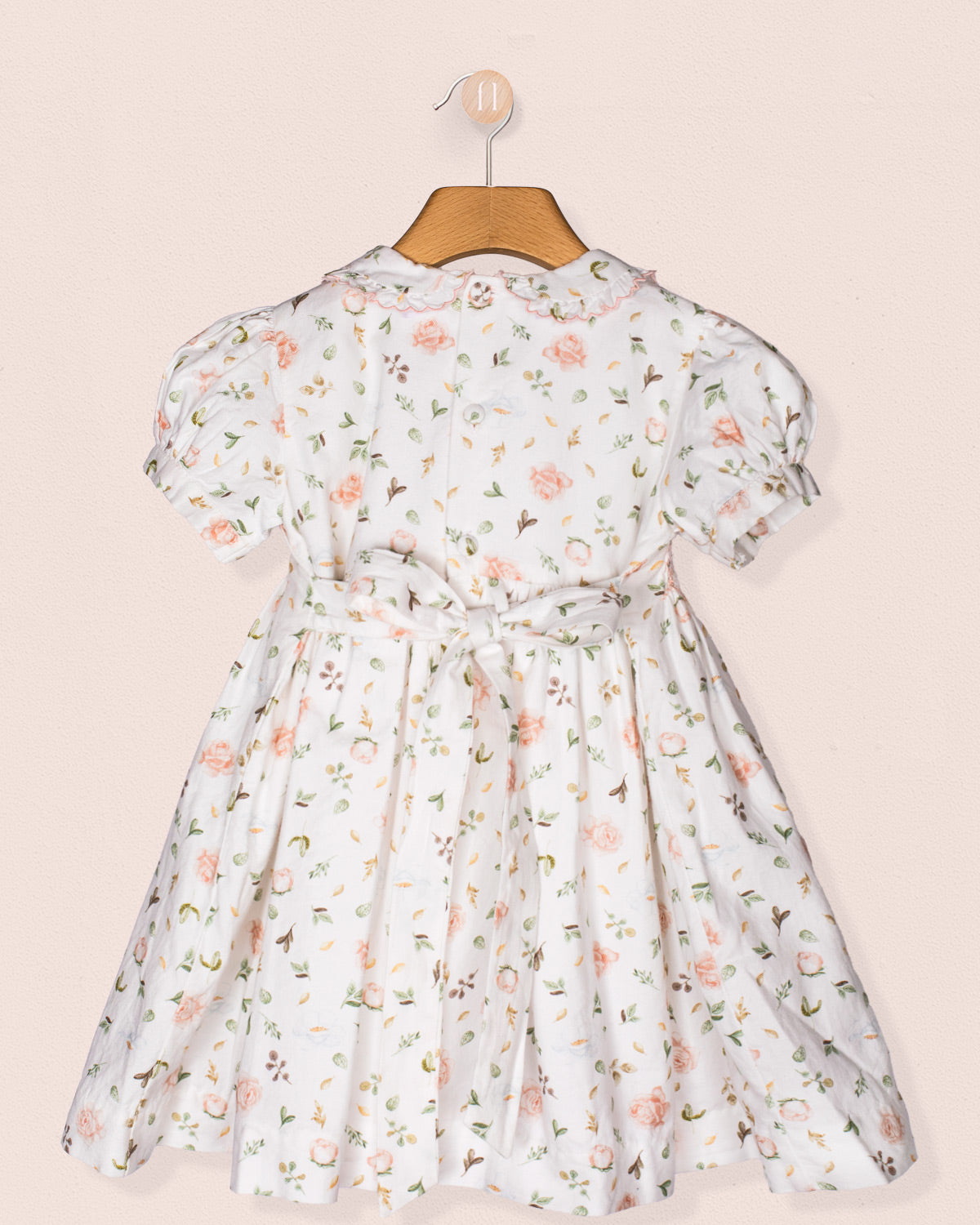 Back view of the Valentina dress showing the button closure, waist tie bow, and all-over floral print, emphasizing craftsmanship and silhouette detail.