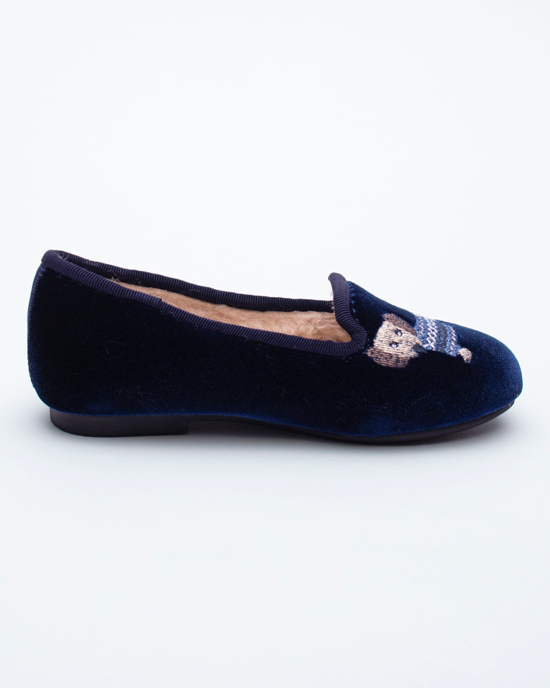 Navy blue velvet flat shoe with a decorative bow on a white background