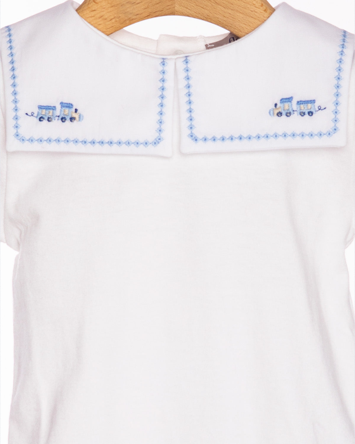 White shirt with blue embroidered details on a hanger