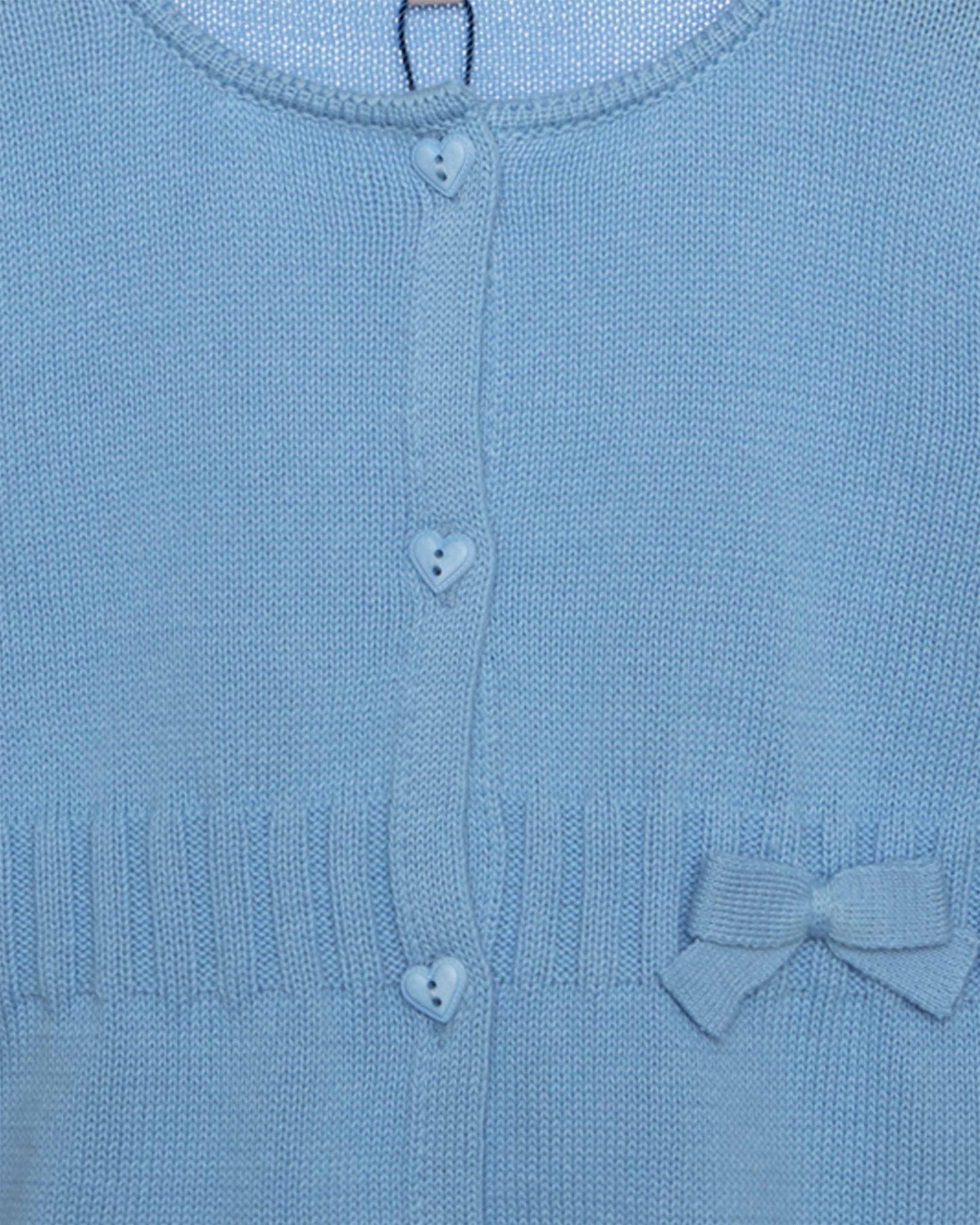 Close-up of a blue knitted cardigan with heart buttons and a bow detail.