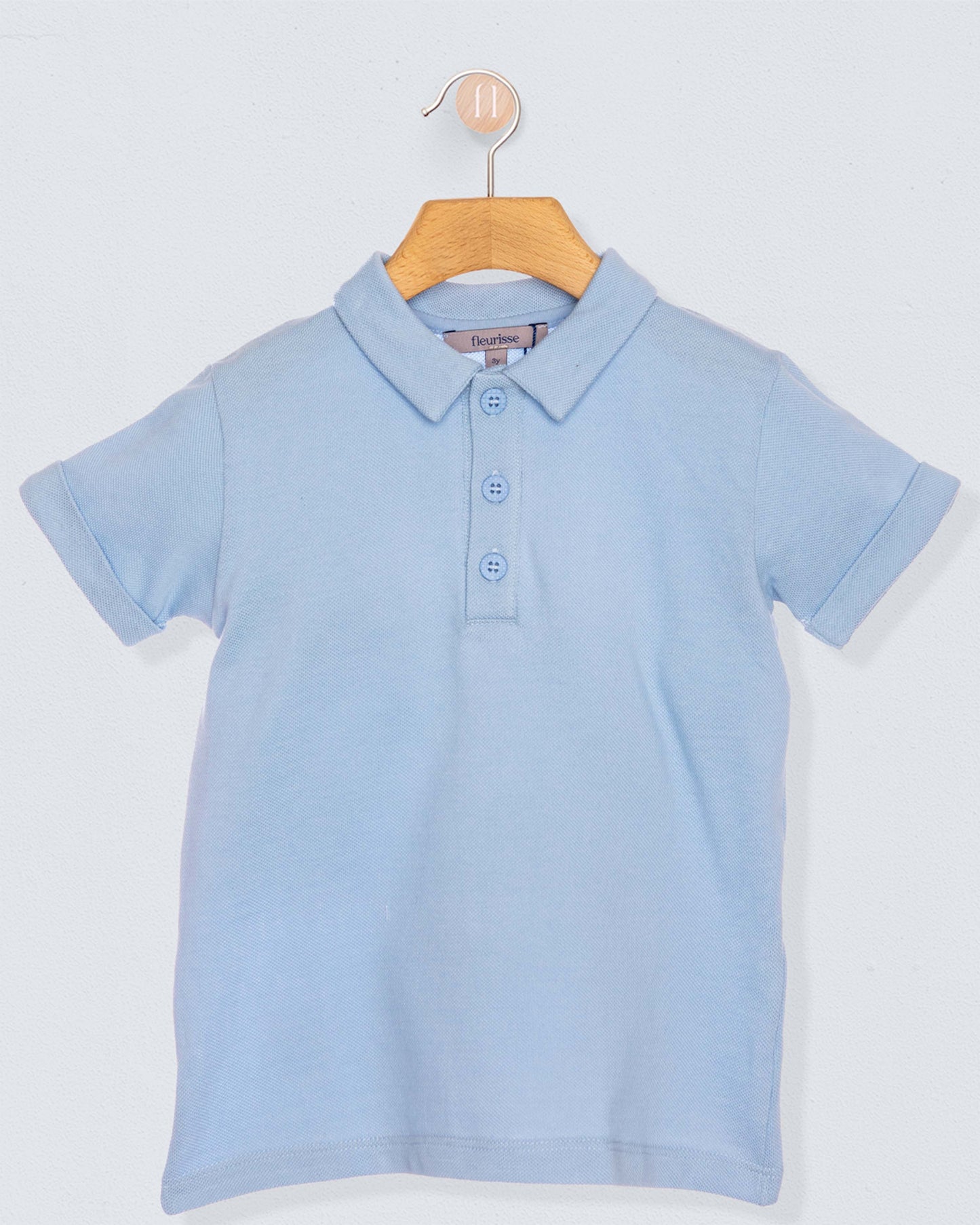 Light blue polo shirt on a wooden hanger against a light gray background