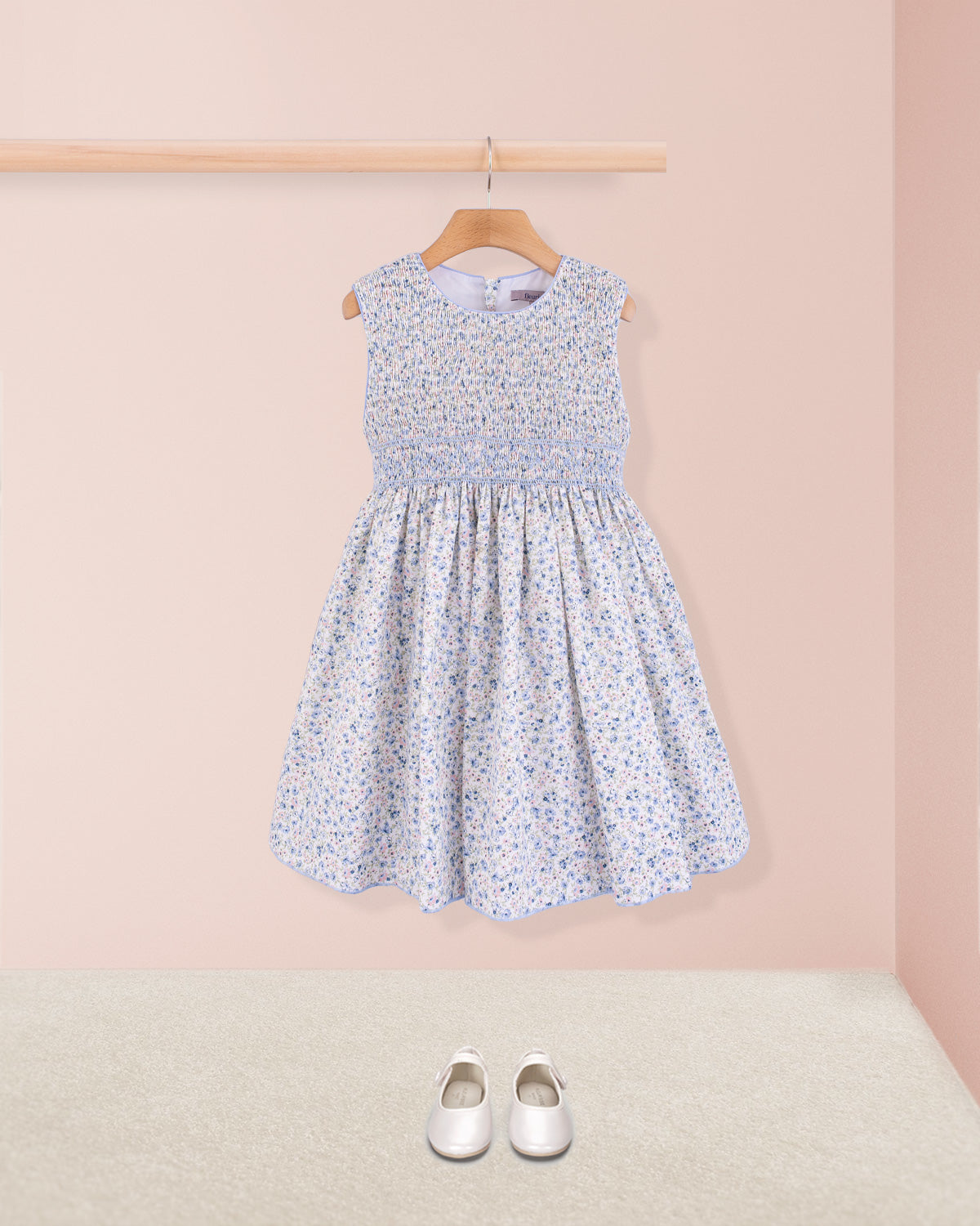 Front view of the Amandine Florencia Blue Floral Dress paired with white shoes, styled simply without accessories on a pink background.