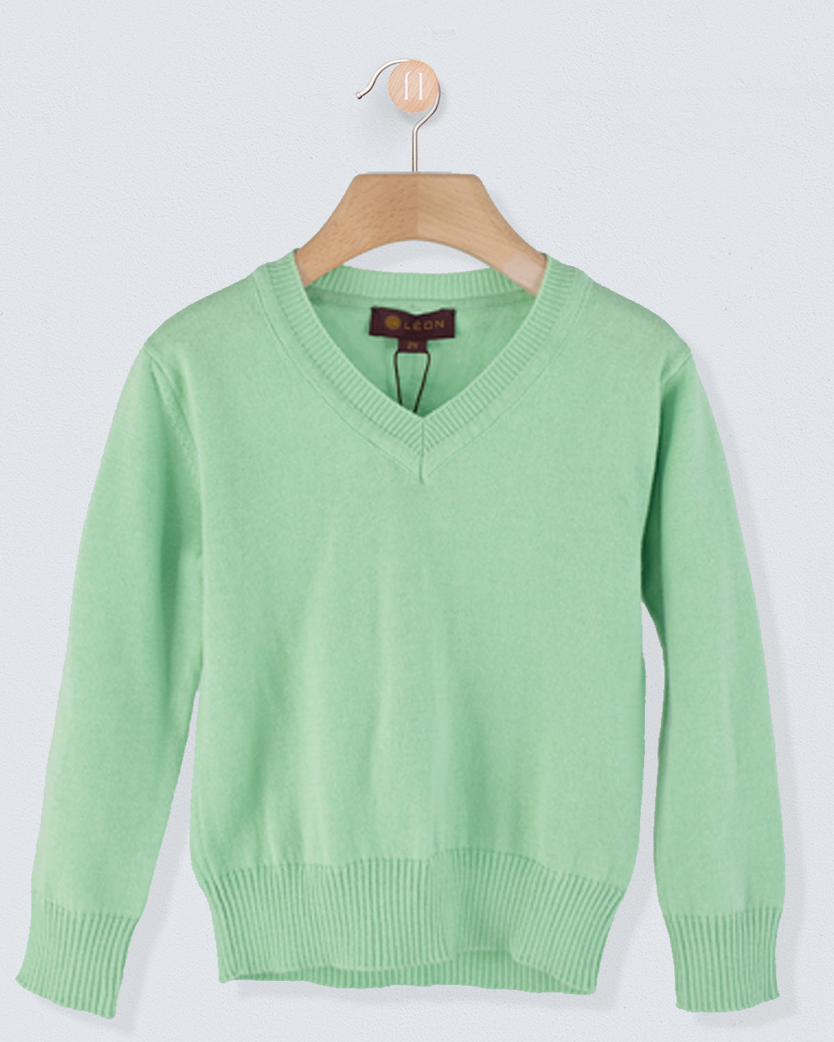 Front view of the Arnaud Moss Cotton Sweater in moss green with a V-neckline and ribbed cuffs and hem hanging on a wooden hanger
