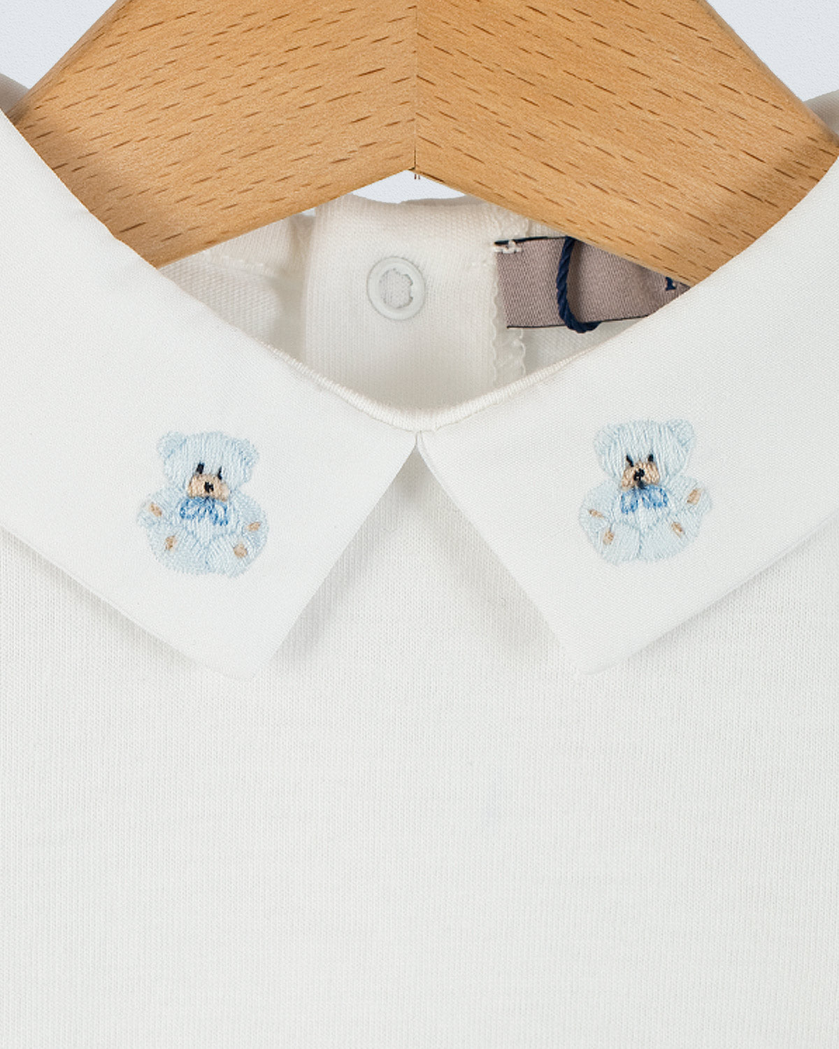 Close-up of the Andreas Baby Onesie’s collar, showing two light blue teddy bear embroideries on each side of the pointed collar.