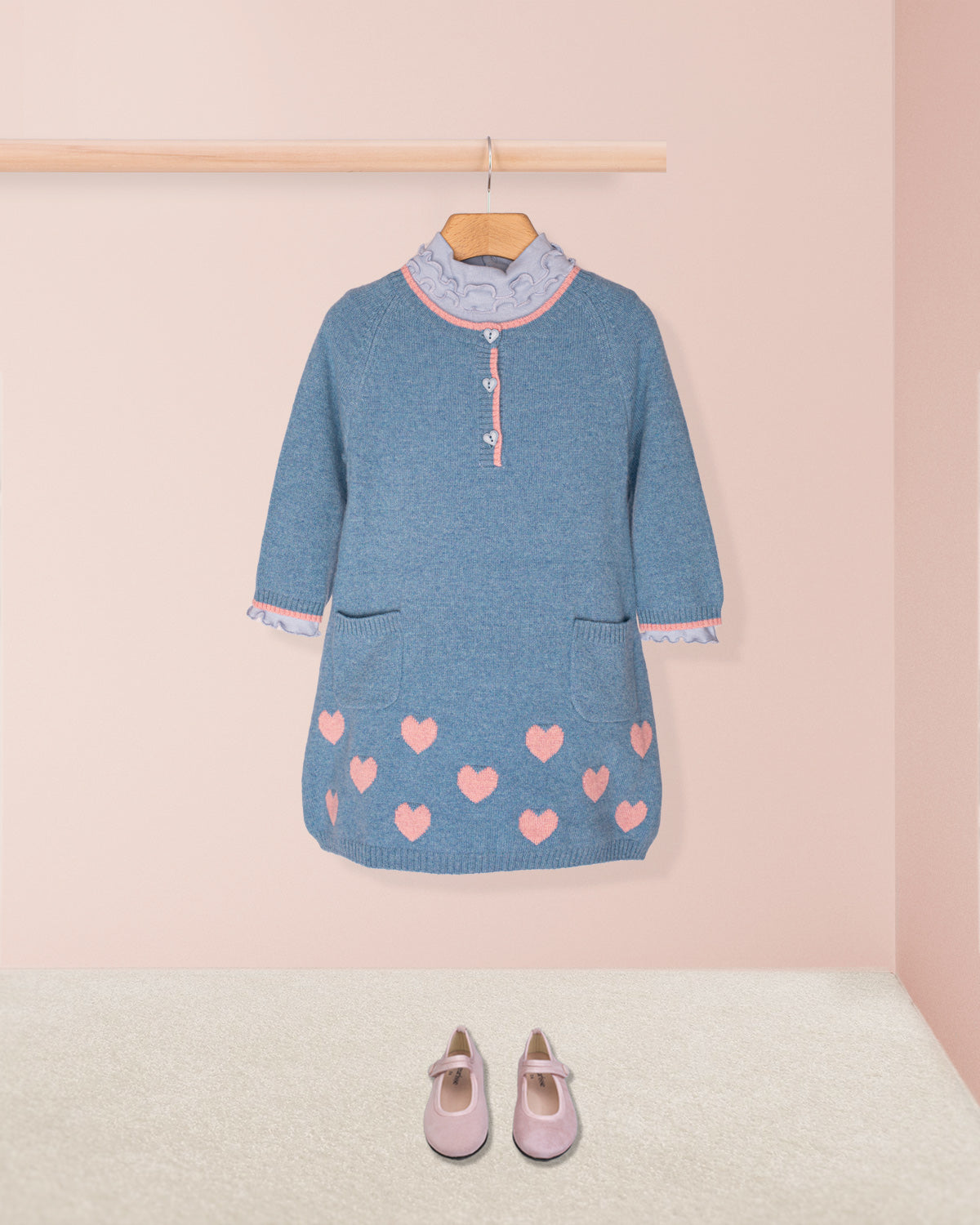 Denim-colored cashmere hearts dress in blue and pink, along with a light blue turtle neck and pink suede shoes in a dressing room