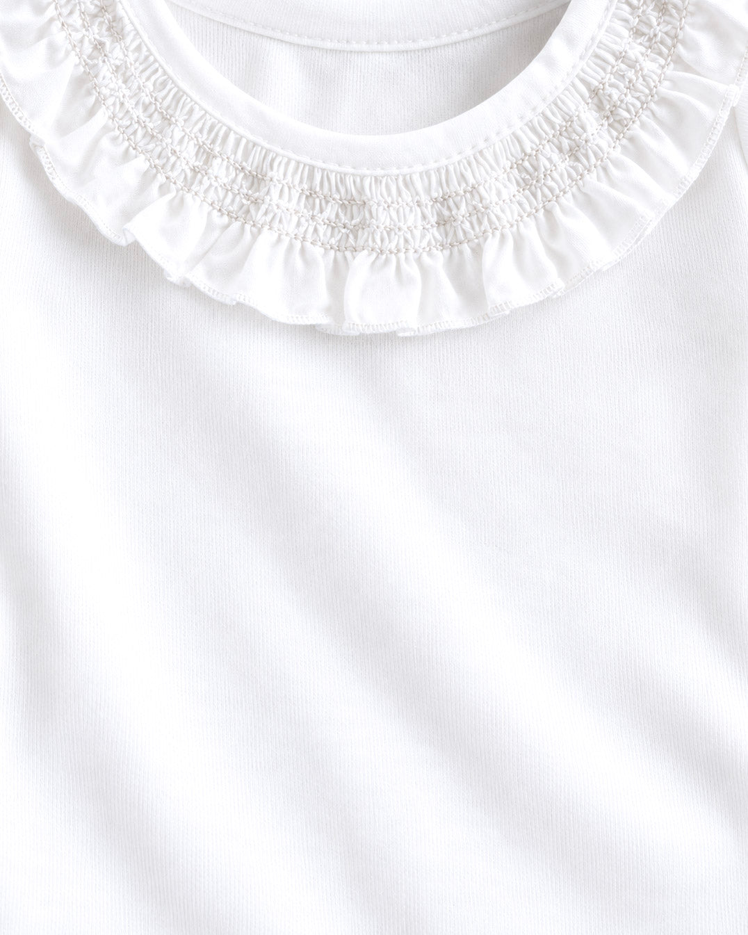 Close-up of a white top with a ruffled smocked crew neck.