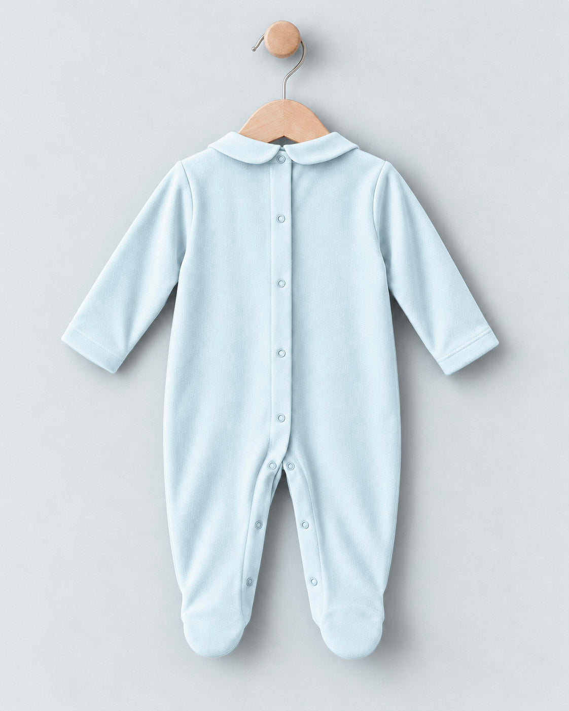 A light blue baby footed sleeper with a Peter Pan collar and snap-button front, hanging on a wooden hanger against a light gray background.