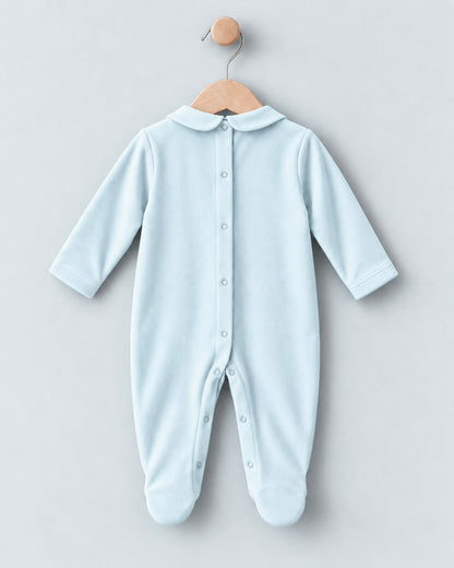 A light blue baby footed sleeper with a Peter Pan collar and snap-button front, hanging on a wooden hanger against a light gray background.