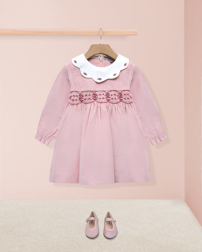 Pink dress with white collar on a hanger against a pink background