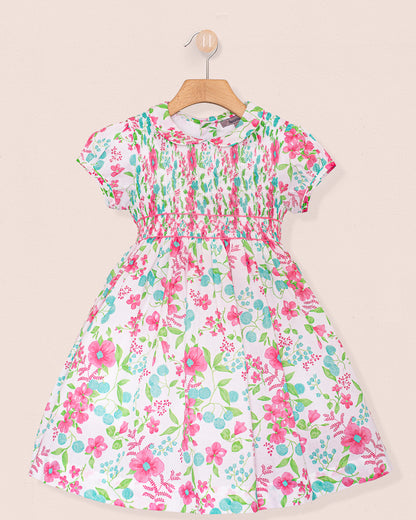 Front view of the Amanda Palm Beach Floral Smocked Dress, featuring a fully hand-smocked bodice, short puff sleeves, and a full skirt with pink, green, and turquoise floral print on white cotton fabric.