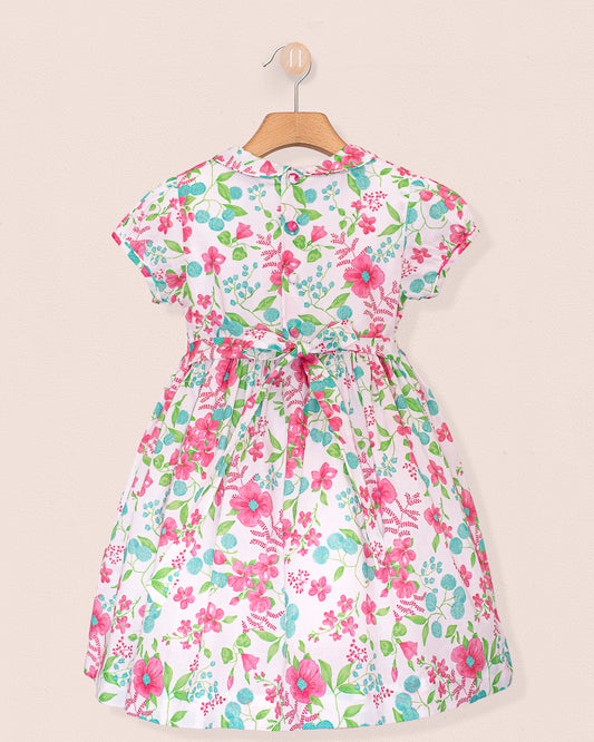 Back view of the Amanda Palm Beach Floral Smocked Dress, showing fabric-covered buttons down the back, a matching sash tied into a bow at the waist, and the same floral print throughout.