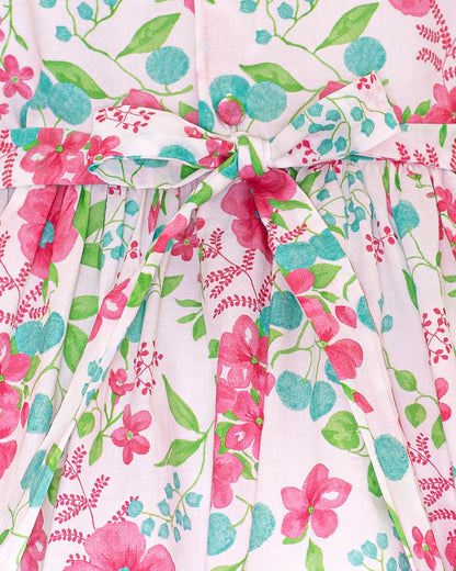 Close-up of the Amanda Palm Beach Floral Smocked Dress showing the waist sash tied into a bow, with detailed view of the pink and green floral cotton fabric and stitching.