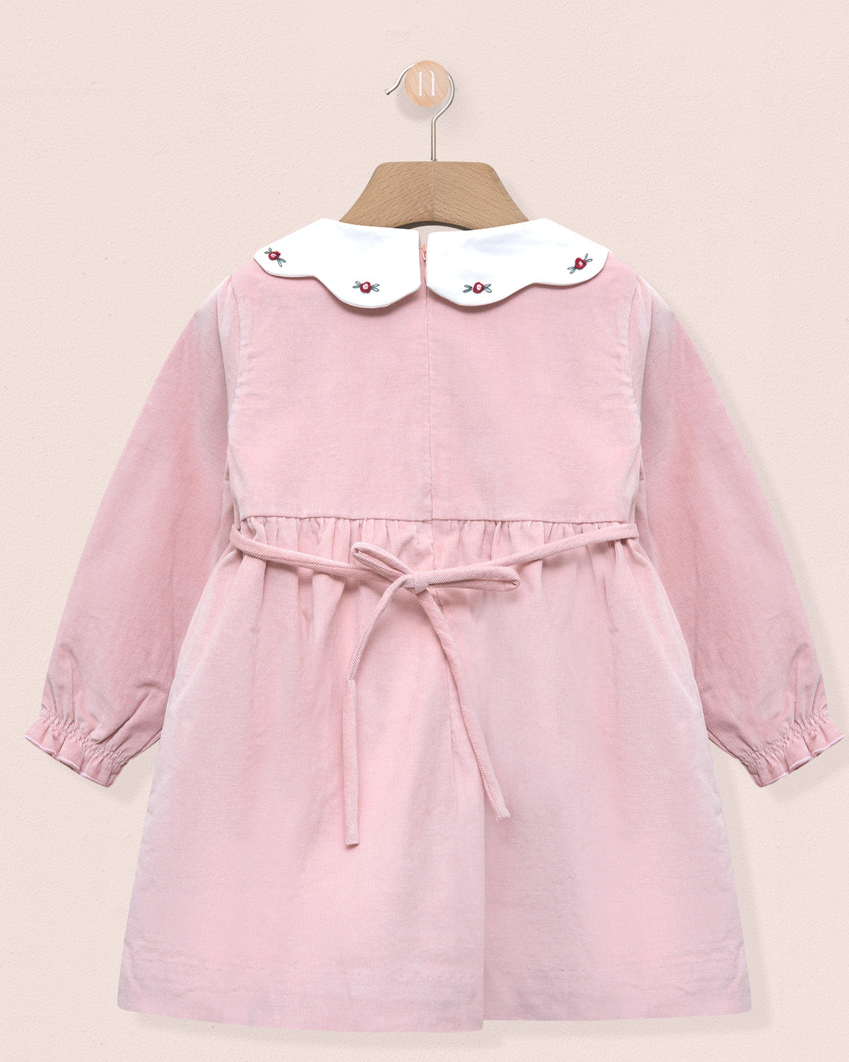 Pink dress with white collar on a beige background