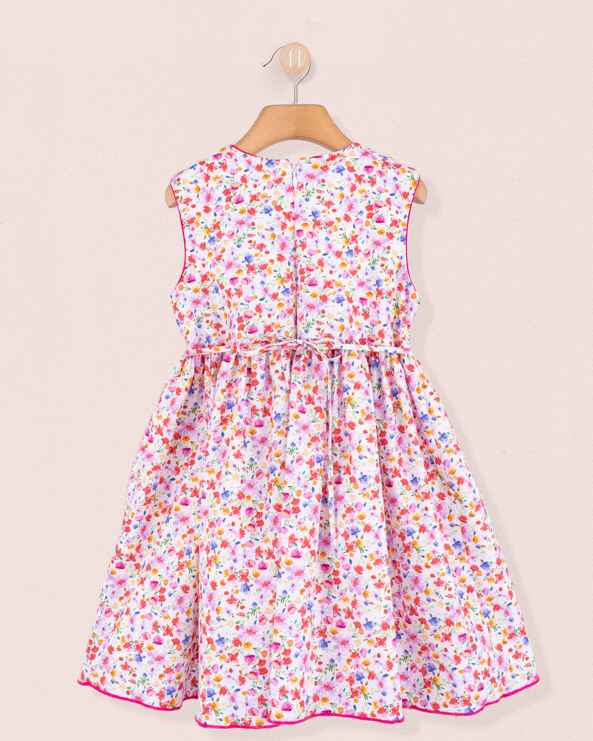 Back view of the Amandine Veneto Hot Pink Garden Smock dress featuring a concealed zip closure and gathered skirt in a lively floral print on white cotton.