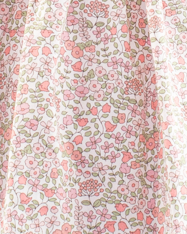 Close-up of the Baby Amelie Garden Pink Set fabric showing pink and coral floral print on white cotton with green leaf detailing