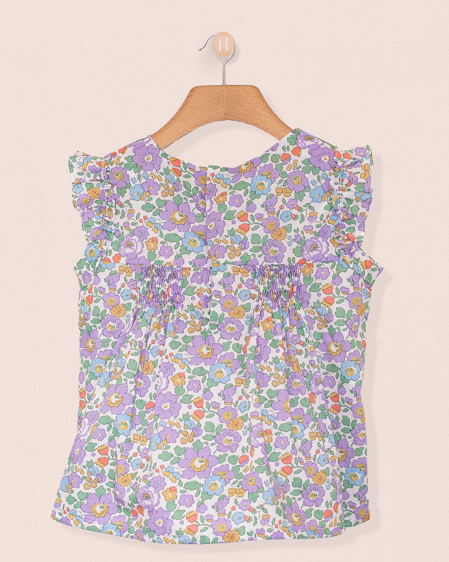 Back view of the Amelie Liberty Betsy Lavender Tunic featuring ruffled sleeves and a hidden snap opening, in a colorful Liberty floral pattern on lightweight cotton.
