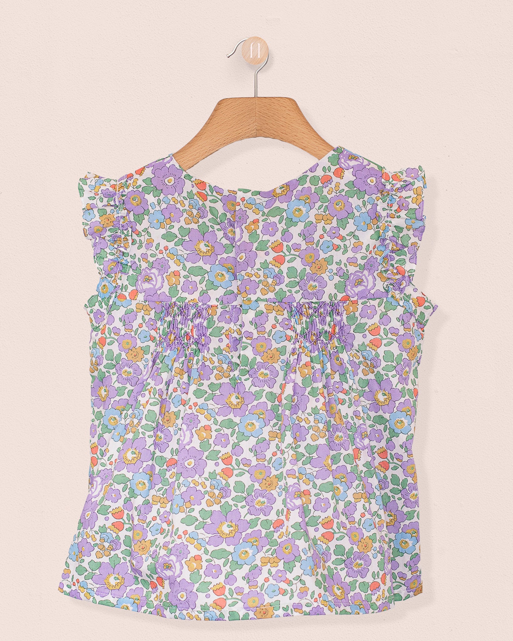 Back view of the Amelie Liberty Betsy Lavender Tunic featuring ruffled sleeves and a hidden snap opening, in a colorful Liberty floral pattern on lightweight cotton.