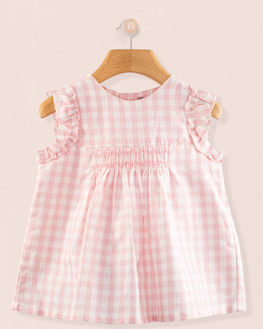 Front view of the Amelie Pink Gingham Linen Tunic, a sleeveless A-line top with hand-smocked detailing, soft ruffled sleeves, and a pale pink and white gingham check pattern.
