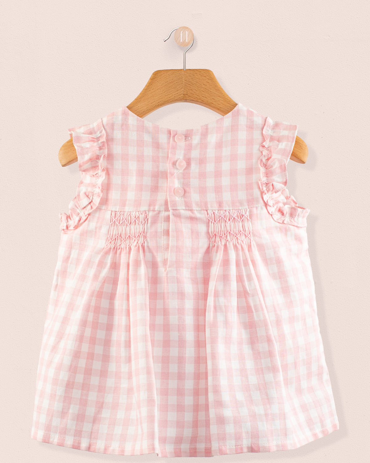 Back view of the Amelie Pink Gingham Linen Tunic showing a delicate smocking detail and a concealed snap closure in a pale pink and white gingham linen blend.