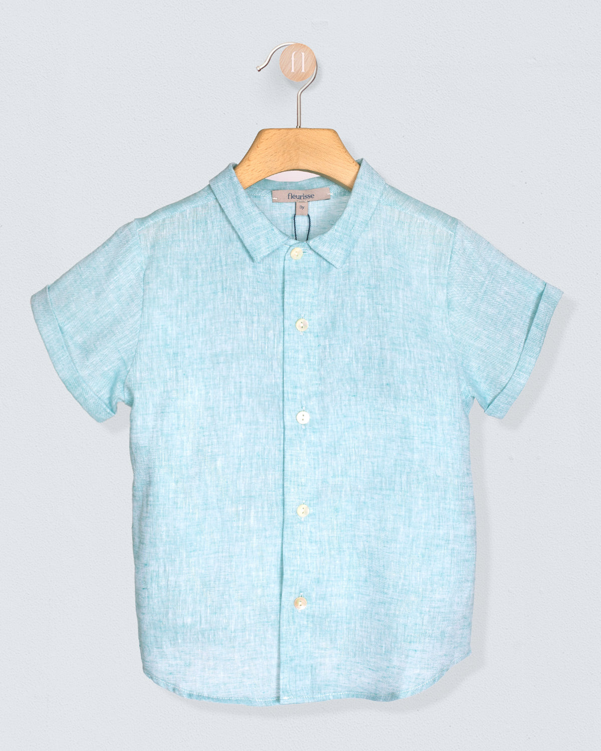 Aqua short-sleeve shirt on a hanger against a light gray background