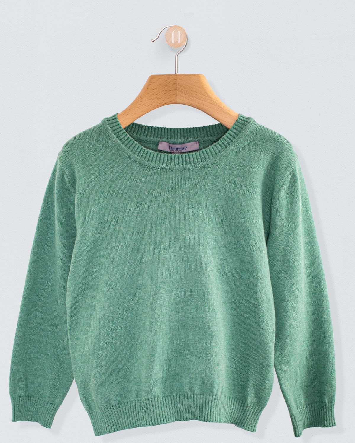 Front view of the Arthur Mélange Cotton Crew Neck sweater in cypress green with a ribbed crew neckline and cuffs hanging on a wooden hanger