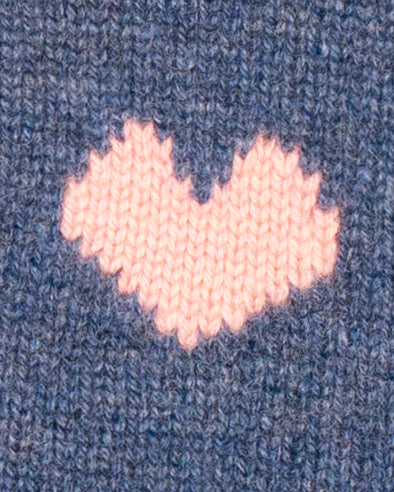 Close-up of Pink knitted heart on a blue textured fabric background