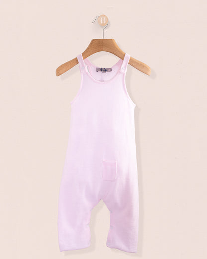 Light pink cotton knit baby overall hanging on a wooden hanger against a pale pink background