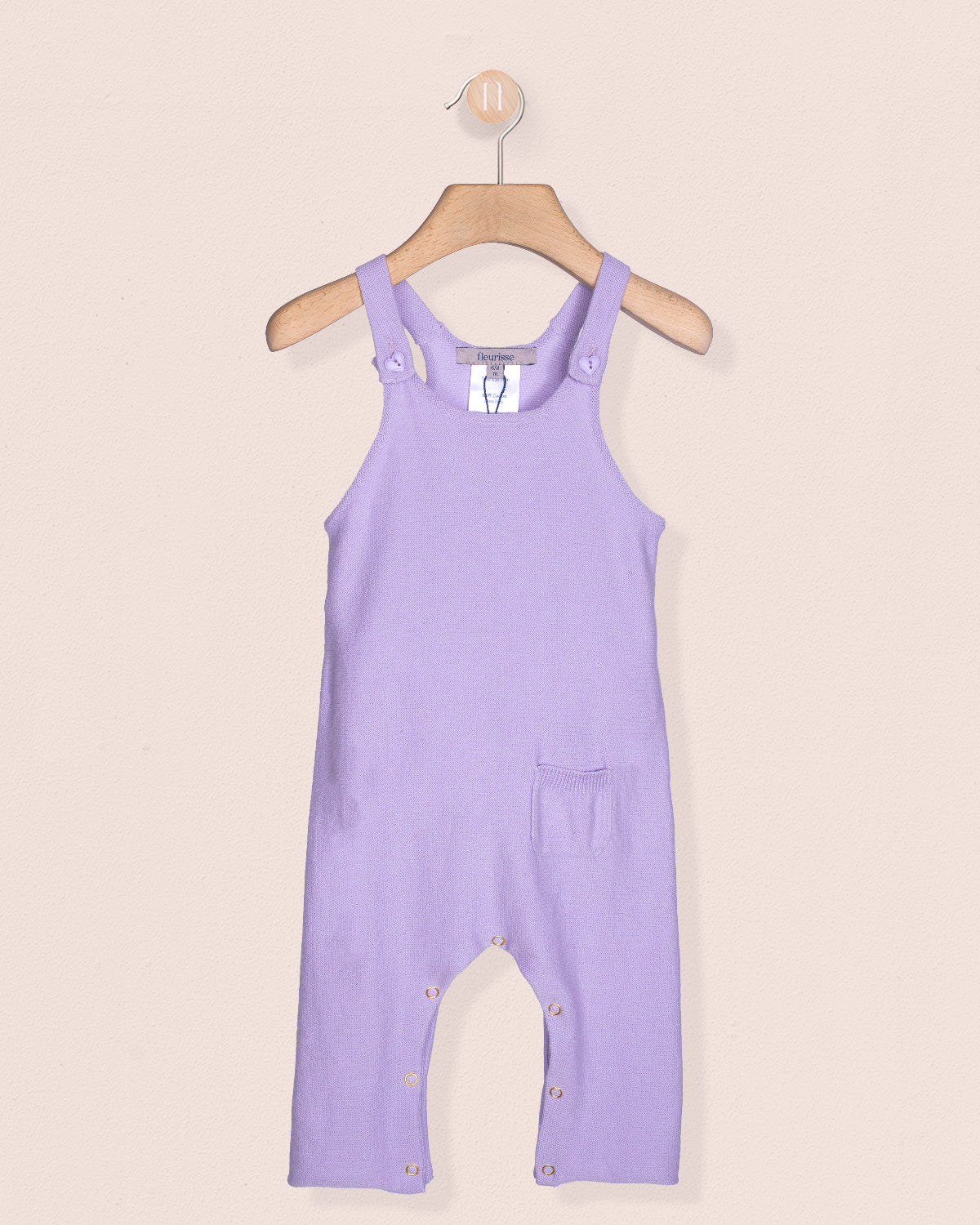 Lavender overalls on a hanger against a beige background