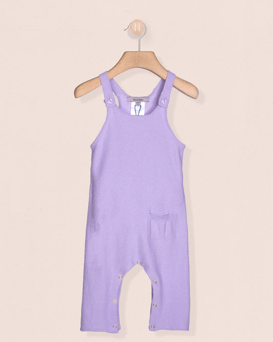 Lavender overalls on a hanger against a beige background