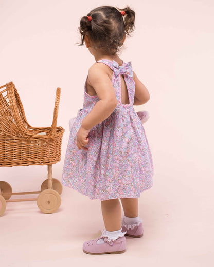 Girl turned to the back, wearing Ibiza Liberty Michelle Blush dress showing the bow and trimming on the back of the dress